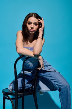 Moda kıyafetli şık bir genç kadın çarpıcı mavi bir ortamda güzellik ve kendine güven gösteriyor..