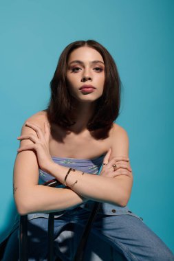 Şık genç kadın zarif pozlar veriyor, modern kıyafetlerini ve güzel özelliklerini vurguluyor..