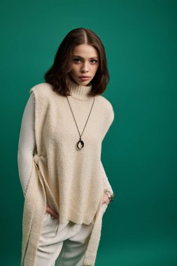 Şık, genç bir kadın kendine güvenen yeşil bir arka planı olan şık bir elbiseyle poz veriyor..