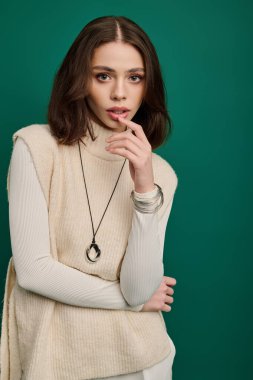 Genç bir kadın cesur yeşil bir zemine karşı moda anlayışını sergiliyor..