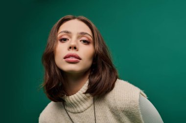 Şık giyinmiş genç bir kadın kendine güvenerek poz veriyor, eşsiz güzelliğini ve çekiciliğini vurguluyor..