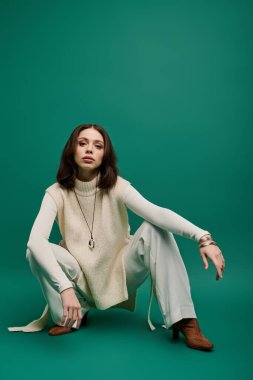 Şık, genç bir kadın kendine güvenerek çömeliyor, modern kıyafetlerini zarif bir pozla sergiliyor..