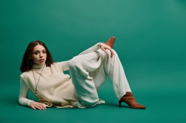 Güzel, genç bir kadın, çarpıcı yeşil bir arka planda şık bir elbiseyle tarzını sergiliyor..