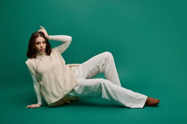 Güzel genç bir kadın zarif bir şekilde şık bir şekilde poz verir cesur yeşil bir zemine karşı.