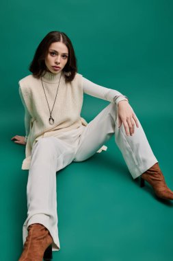 Şık bir kadın geniş bacaklı pantolonları ve şık aksesuarlarıyla zarif bir şekilde oturur..