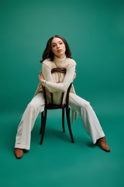 Şık bir kadın zarif bir şekilde bir sandalyeye oturur ve şık kıyafetlerini sergiler..