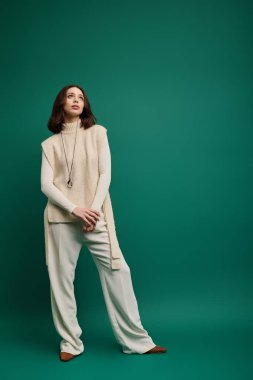 Modaya uygun genç bir kadın şık bir elbiseyle canlı yeşil bir arka plana karşı şık bir poz verir..