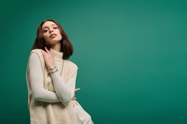 Zarif genç bir kadın kendine güvenerek poz verir, canlı bir şekilde şık bir kıyafet giyer..