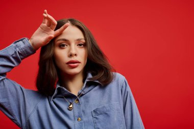 Şık genç bir kadın çarpıcı bir kırmızı zemine karşı güzelliğini ve yeteneğini sergiliyor..