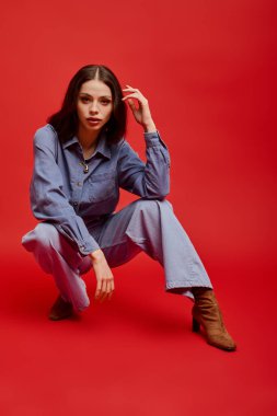 Şık bir genç kadın kot giyip zarif pozlar veriyor, kendine güven ve güzellik saçıyor..