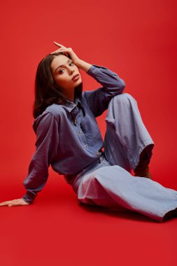 Genç bir kadın zarif bir şekilde yerde oturmuş modern moda eğilimlerini sergiliyor..