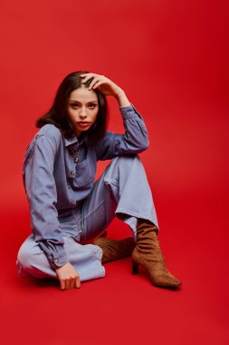 Zeminde oturan zarif genç bir kadın, zerafet ve moda anlayışı yayıyor..