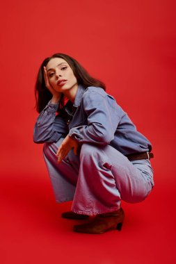 Modaya uygun genç bir kadın, kendine güvenerek eğiliyor, kendine has tarzını çarpıcı bir ortamda ifade ediyor..