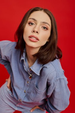 Güzel genç kadın şık bir şekilde kot giyip, cazibe yayıyor ve modaya uygun bir şekilde poz veriyor..