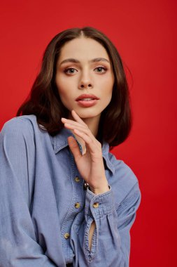 Genç, güzel bir kadın zarif bir şekilde poz verir. Şık bir gömlek giyer, kendine güven ve tarz yayar..