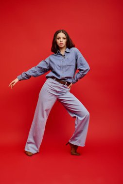 Modaya uygun genç bir kadın dikkat çekici kırmızı bir ortamda eşsiz tarzını sergiliyor..