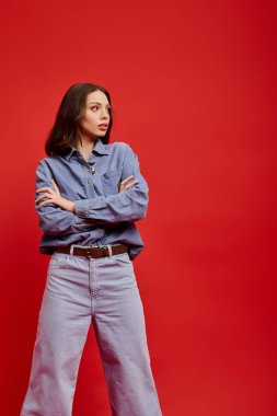 Güzel genç bayan kendine güvenen bir şekilde poz veriyor. Kırmızı arka planda..