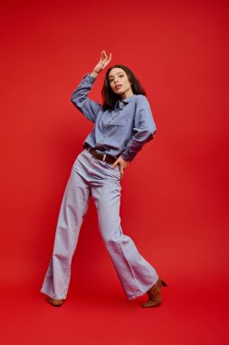 Şık kot elbiseli güzel bir kadın cilalı zeminde neşeyle dans ediyor, kendine güveni yayıyor..