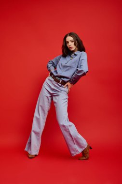 Çarpıcı bir kırmızı ayar içinde, şık genç bir kadın kendine güveni ve zarafetiyle havasını atıyor..