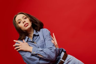 Genç bir kadın şık moda anlayışını çarpıcı bir kırmızı ayara güvenerek sergiliyor..