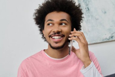 Gülümseyen genç adam telefonda konuşuyor, sıcak bir oturma odasında sıcaklık ve neşe saçıyor..