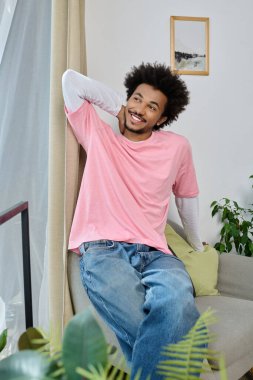 Genç, çekici bir adam rahat bir şekilde koltukta oturur, şık ve rahat bir şekilde gülümser..