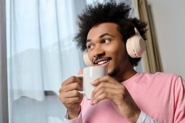 Parlak bir sabah sahnesi, genç bir adamın rahat bir ortamda kahve ve müziğin tadını çıkardığını gösteriyor..