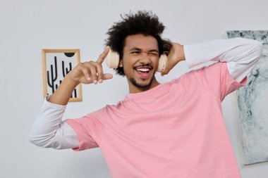 Dinamik genç adam şık bir odada kulaklıkla müzik dinlerken neşeyle dans eder..
