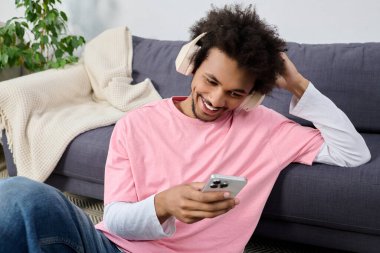 Mutlu genç adam evde yerde otururken gülümsüyor ve müzikten hoşlanıyor..