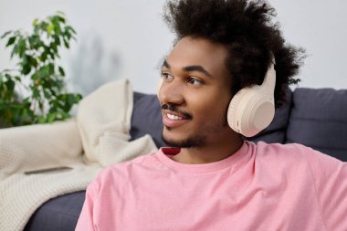 Genç yakışıklı bir adam kablosuz kulaklıkla müzik dinlemekten hoşlanır, rahat bir yerde gülümser..