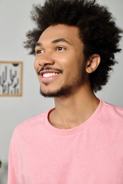 Genç yakışıklı bir adam sıcak bir şekilde gülümsüyor, evin içinde yeşilliklerle çevrili bir anın tadını çıkarıyor..