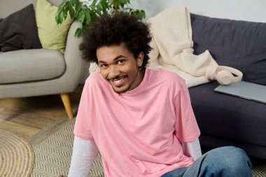 Kıvırcık saçlı genç bir adam yerde rahat bir anın tadını çıkarıyor. Etrafı hoş bir dekorla çevrili..