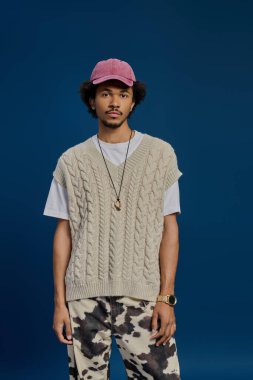 Şık bir genç adam, kendine has moda anlayışını canlı mavi bir arka plana karşı sergiliyor..