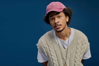 Kıvırcık saçlı çekici bir adam rahat bir ortamda eşsiz bir moda anlayışı sergiliyor..