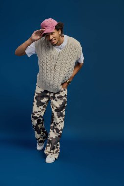 Genç bir adam modaya uygun bir şekilde poz veriyor, benzersiz moda anlayışını ve çekiciliğini vurguluyor..