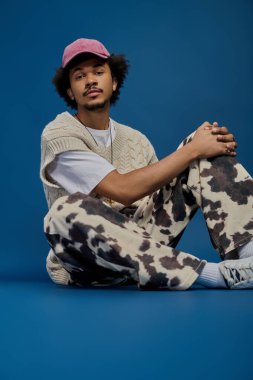 Şık bir genç adam zarif bir şekilde oturur, eşsiz tarzını ve zahmetsiz çekiciliğini sergiler..