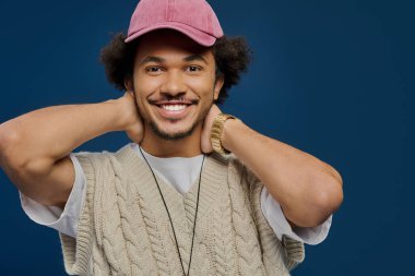 Kıvırcık saçlı neşeli genç bir adam neşe dolu bir anın tadını çıkarıyor, kendine güven ve tarz yayıyor..