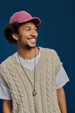 Genç bir adam parlak bir gülümsemeyle, şık örgü süveter ve şapka takarak cazibesini sergiliyor..