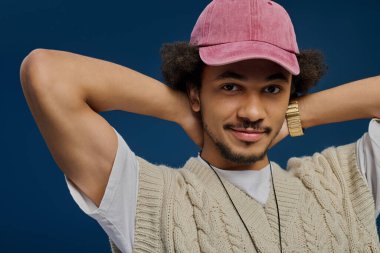 Çekici bir genç adam arkasına yaslanıyor, elleri başının arkasında, neşeyle gülümsüyor..