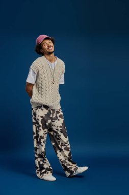 Şık bir genç adam modaya uygun giysiler içinde, eğlenceye hazır bir şekilde gülüyor..