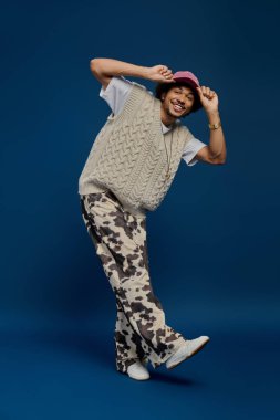 Neşeli genç adam eşsiz moda anlayışını, neşeli pozları ve şık kıyafetleriyle sergiliyor..