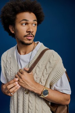 Genç bir adam tarzını örgü bir yelek ve modaya uygun aksesuarlarla sergiliyor..