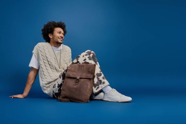 Şık bir genç adam mavi bir zemine yaslanır, rahatlatıcı bir güven yayar..