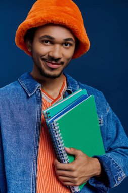 Şık giyinmiş genç ve yakışıklı bir adam elinde yeşil defterlerle kendine güveniyor..