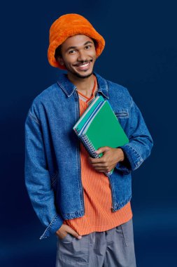 Kendine güvenen genç adam renkli defterlerle şık poz veriyor..