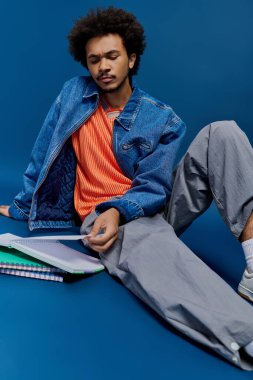 Genç yakışıklı bir adam mavi katta dizüstü bilgisayarlarıyla dinleniyor, düşüncelere dalmış ve şık giyinmiş..