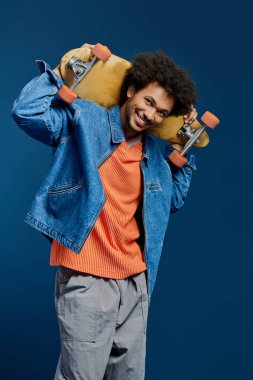 Gülümseyen genç bir adam kafasının üstünde neşeyle bir kaykay tutuyor..