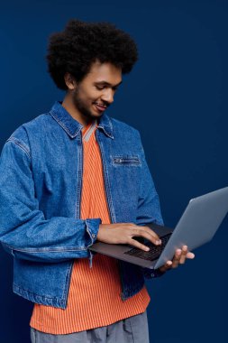 Çekici bir gülümsemesi olan genç bir adam dizüstü bilgisayarında çalışıyor, yaratıcılığını ve tarzını gösteriyor..