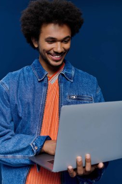 Kıvırcık saçlı bir adam dizüstü bilgisayarıyla meşgul, sakin, profesyonel bir atmosferde neşe saçıyor..