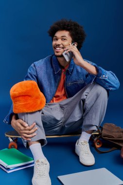 Genç, şık bir adam canlı bir telefon görüşmesi yapar, kaykayının yanında öylesine oturur..